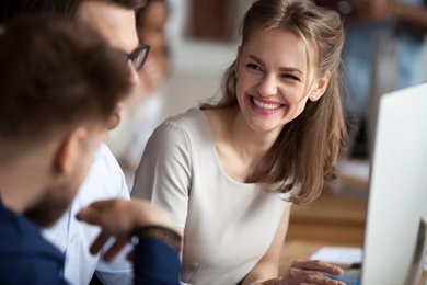 Drei Personen sitzen vor einem Computer und lernen gemeinsam