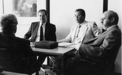 Original schwarz-weiß Foto aus den 70er-Jahren mit einem Round Table von vier männlichen Barcode-Pionieren in Anzug und Krawatte mit einem Aufnahmegerät aus dieser Zeit