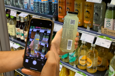 Mann liest mit einem Smartphone eine Flasche Jake's Lemonade aus